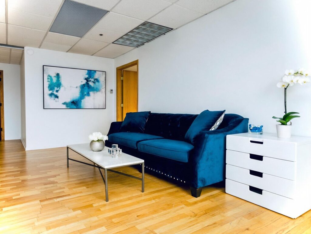 Bright room with a navy velvet sofa, white marble coffee table, white drawer unit with an orchid